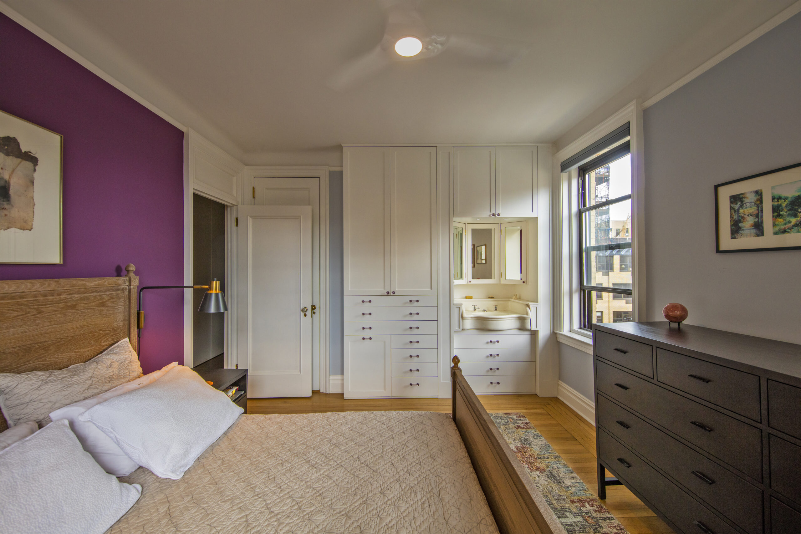 An aubergine-colored accent wall grounds the Prime Bedroom with two clothes closets, a refurbished sink closet.