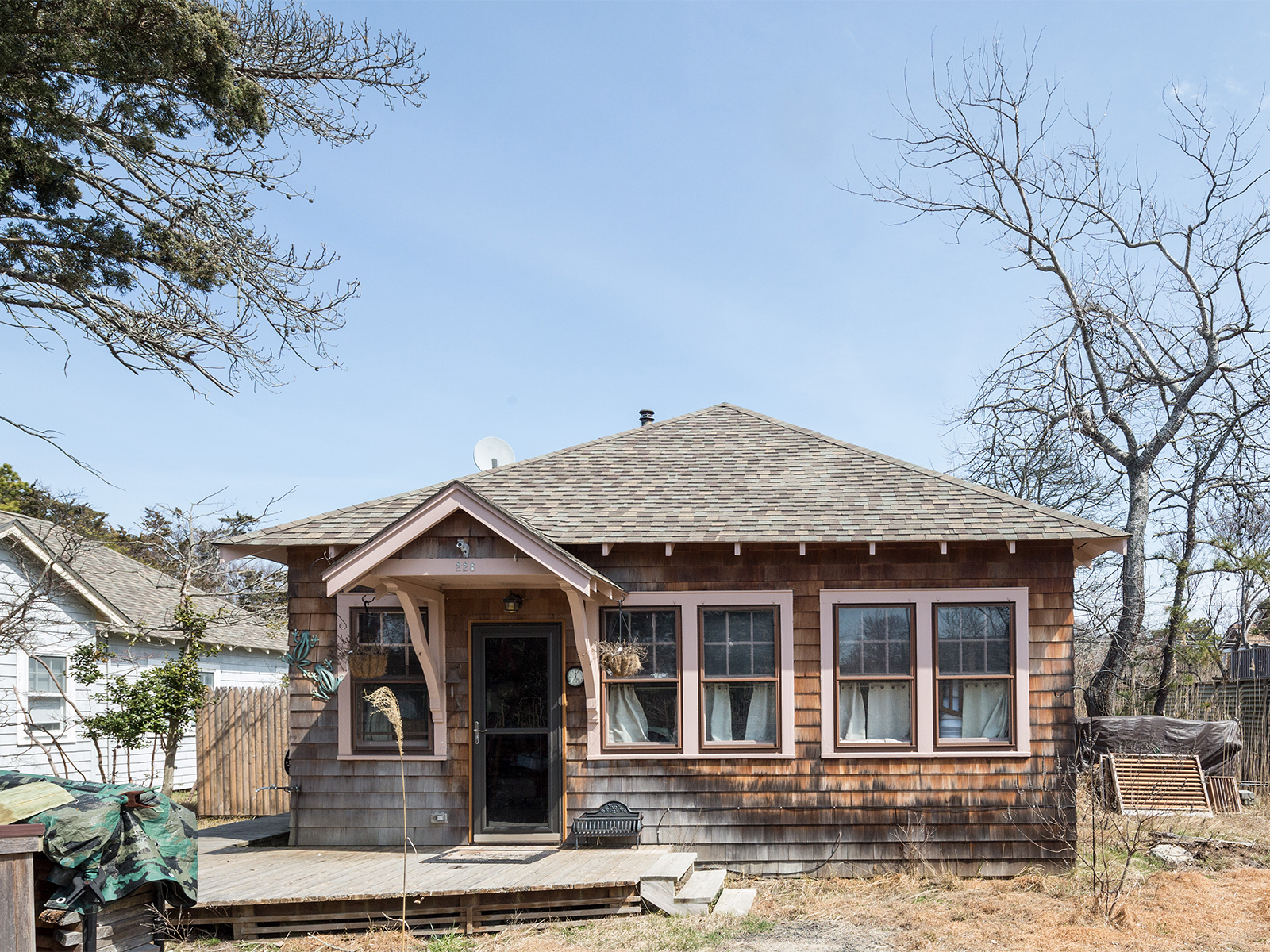 Front view of the wood-shingled house sitting on the ground on a sandy street