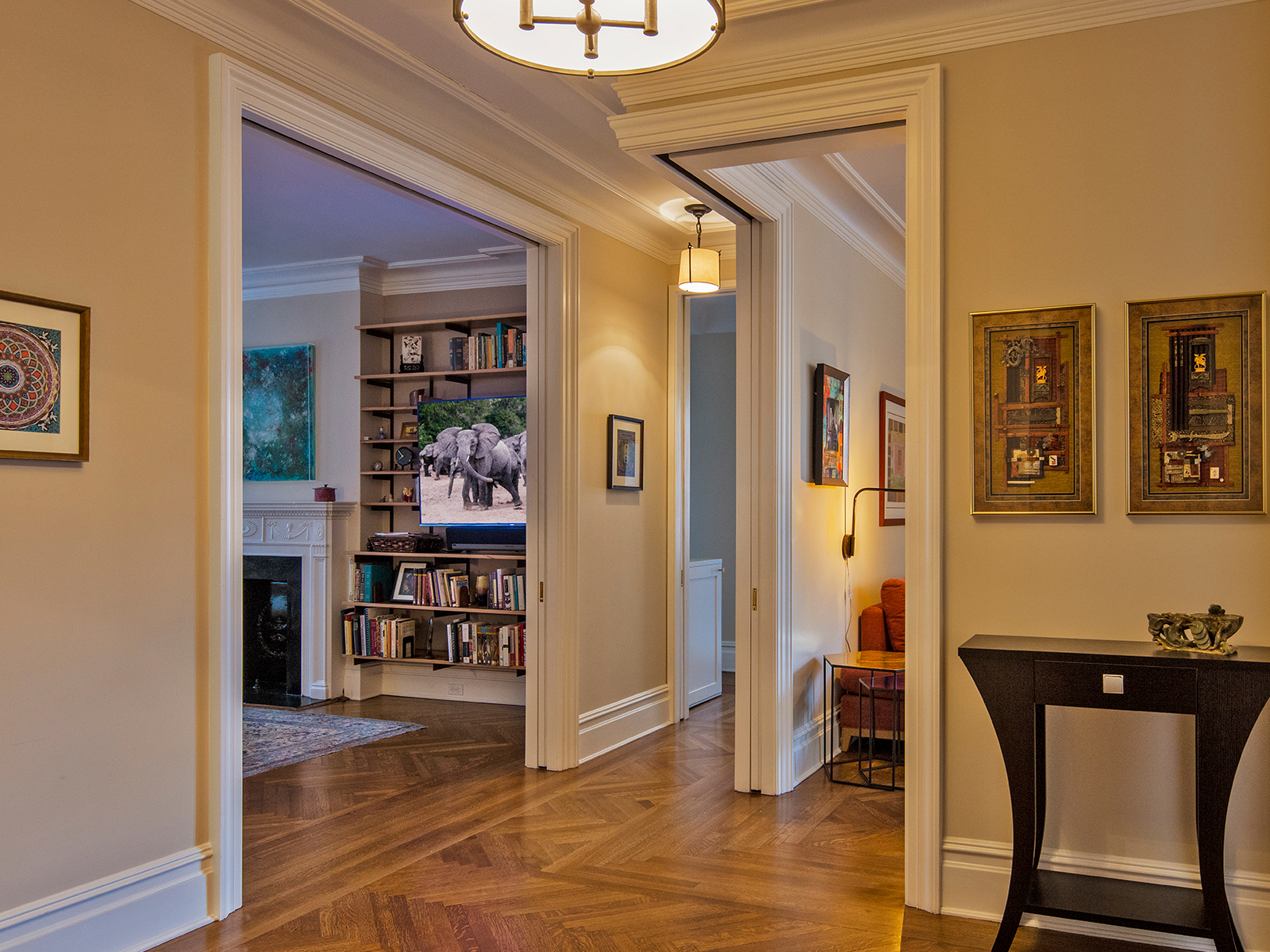 After: The entry vestibule is more spacious, with a deep red accent wall behind a custom built-in storage and bench and new stone mosaic floors