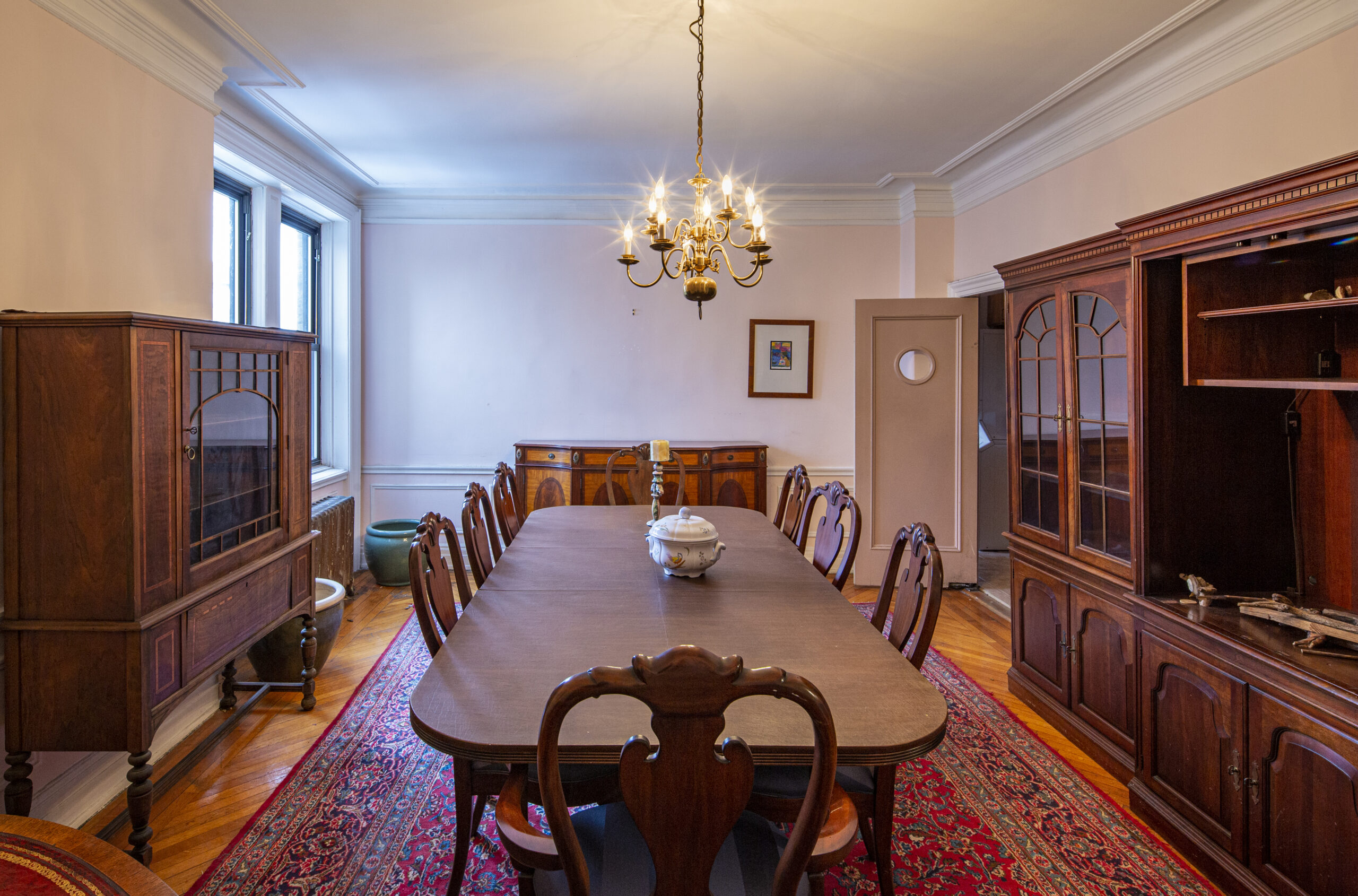 A classic large dining Room with windows in the corner and tall, dark furniture