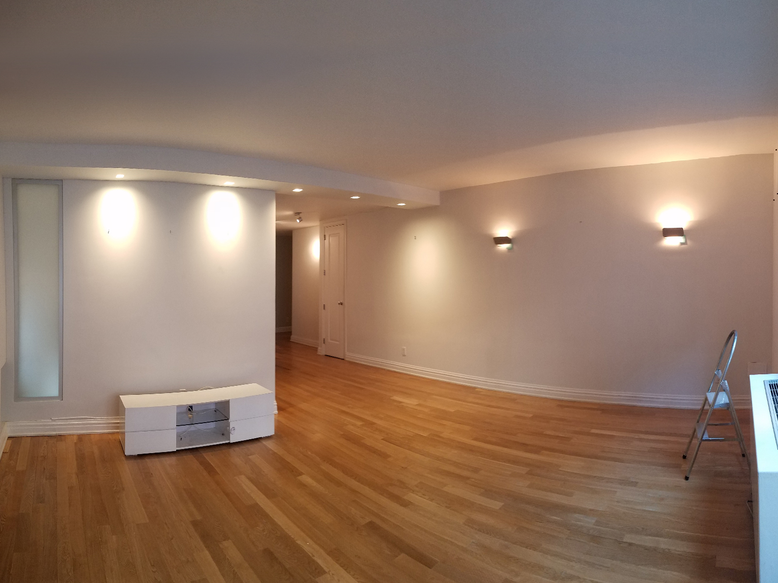 An angled view of an empty Living Room with a corridor beyond