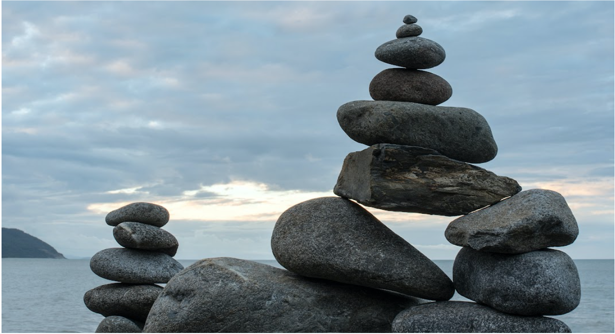 Several stack of grey rocks by a calm ocean under a partly coudy sky