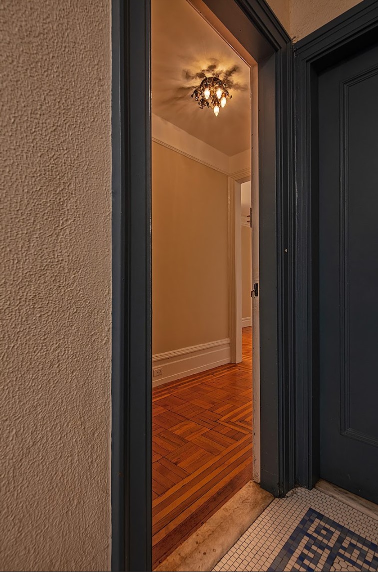 Before: Standing in a narrow vestibule with a wood floor, there are a series of doors ahead, leading in different directions.