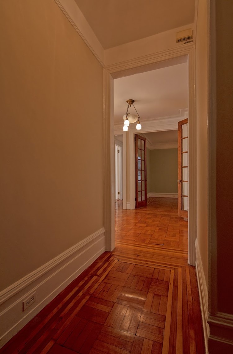 Before: Standing in a narrow vestibule with a wood floor, there are a series of doors ahead, leading in different directions.