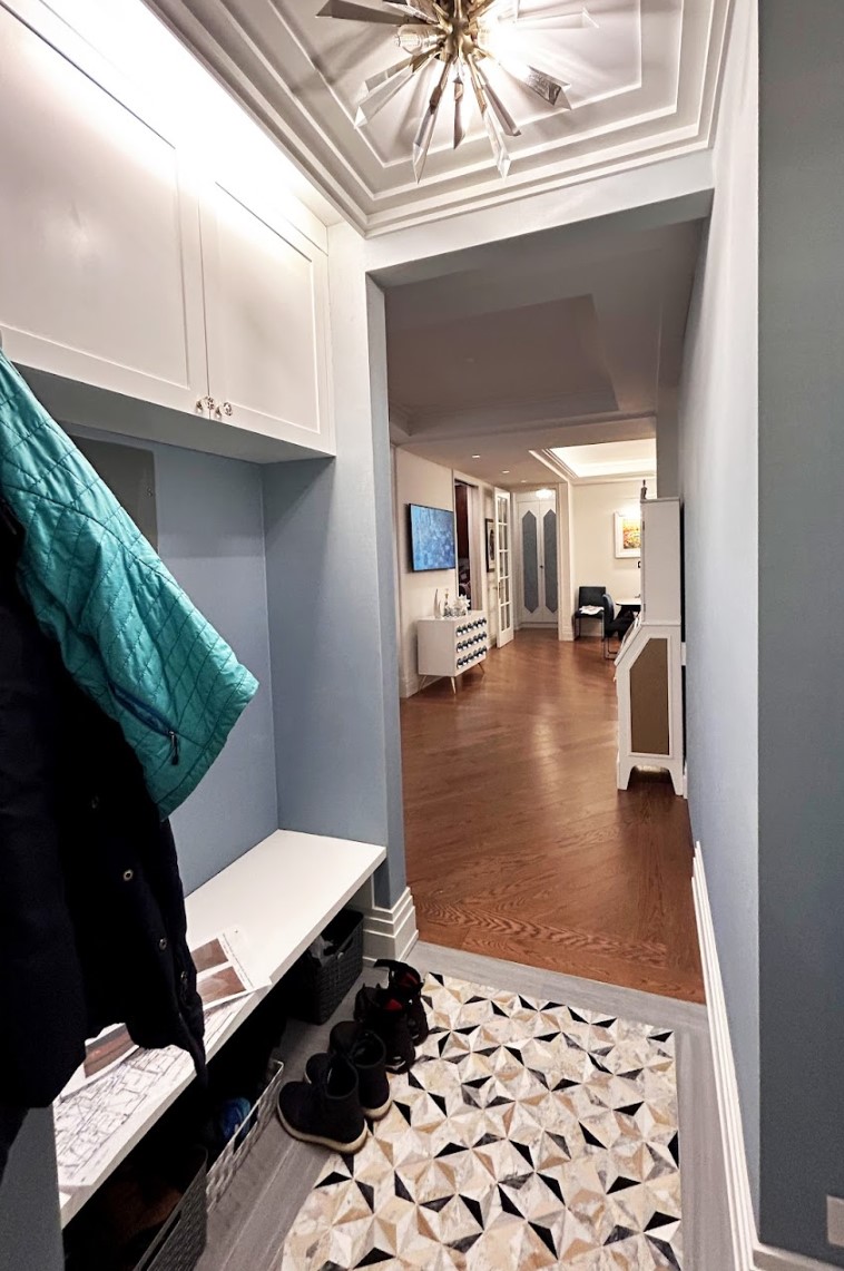 After: The narrow vestibule with new marble mosaic has been widened to include a bench with storage above. The vestibule opens into a widened, uninterrupted view of the apartment.