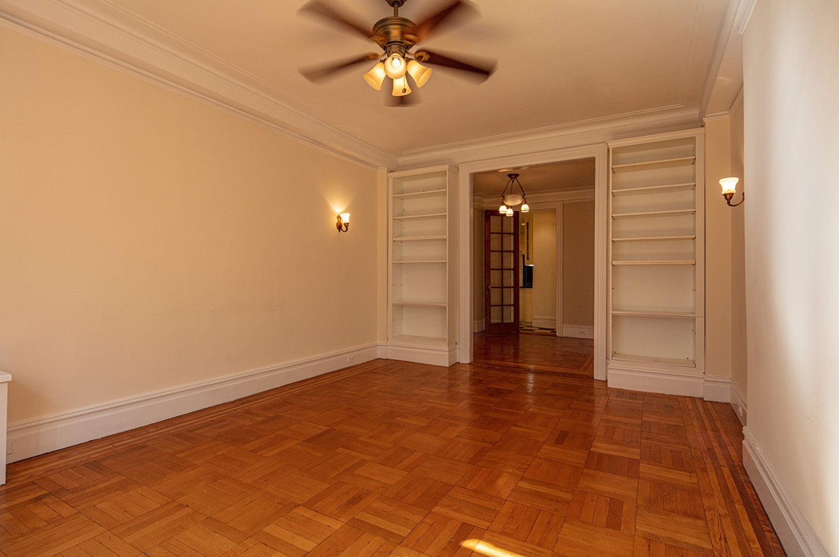 Before: An unfurnished living room has bookcases flanking a double-wide opening of the foyer.