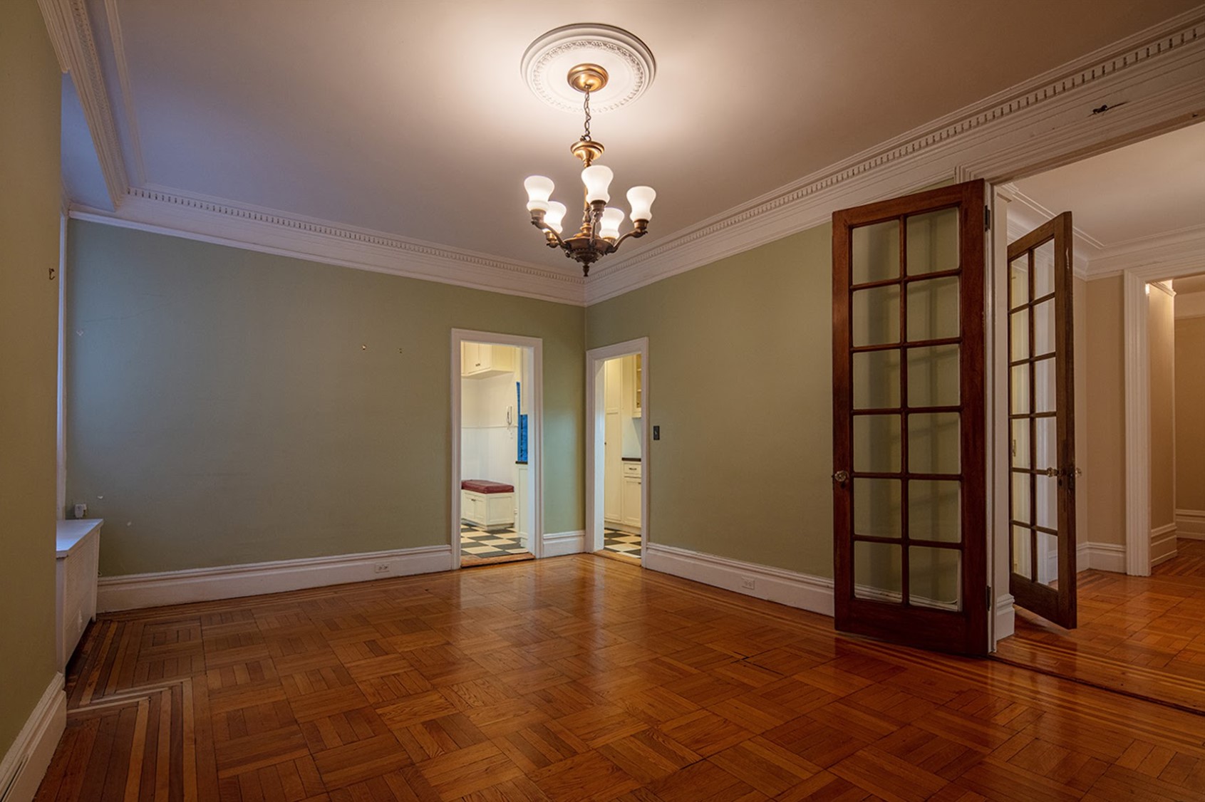 Before: The corner of an unfurnished pre-war dining has 2 narrow doors. The door on the left leads to the Kitchen, and the one on the right to the Butler’s Pantry.