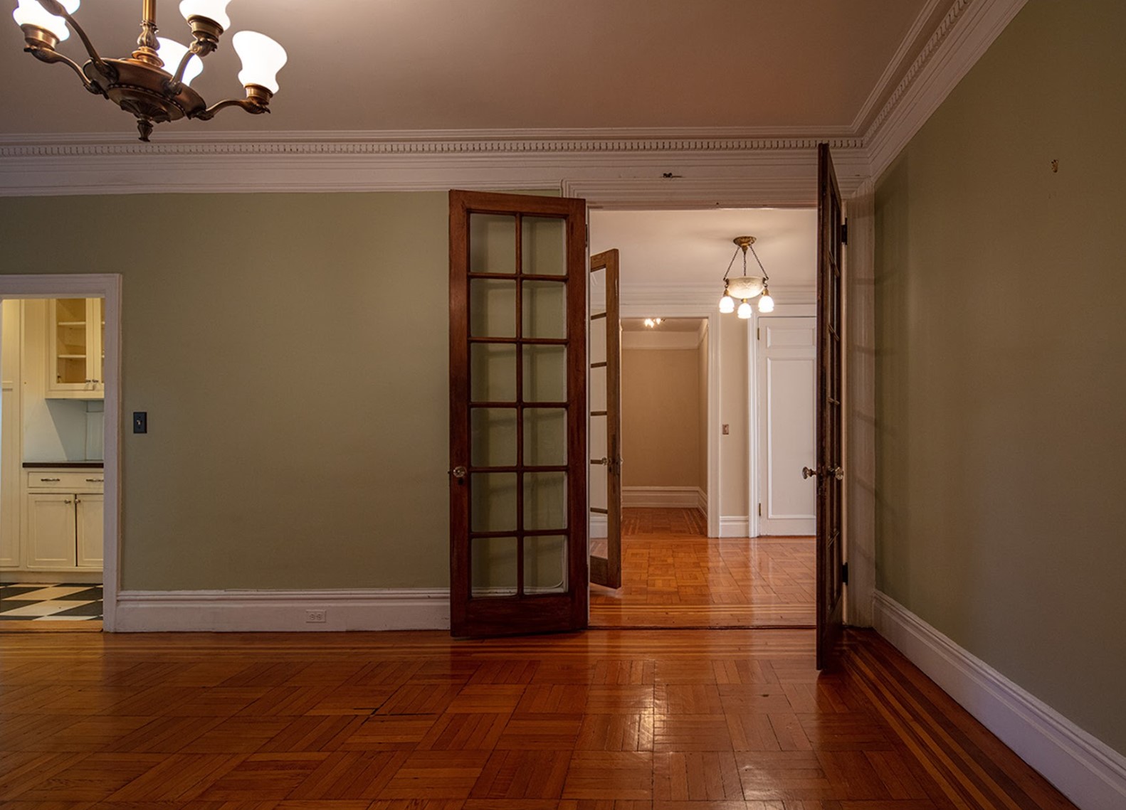 Before: Unfurnished pre-war dining room viewed from a corner, French doors to the Foyer are straight ahead andthe narrow door to Butler’s Pantry is on the left.