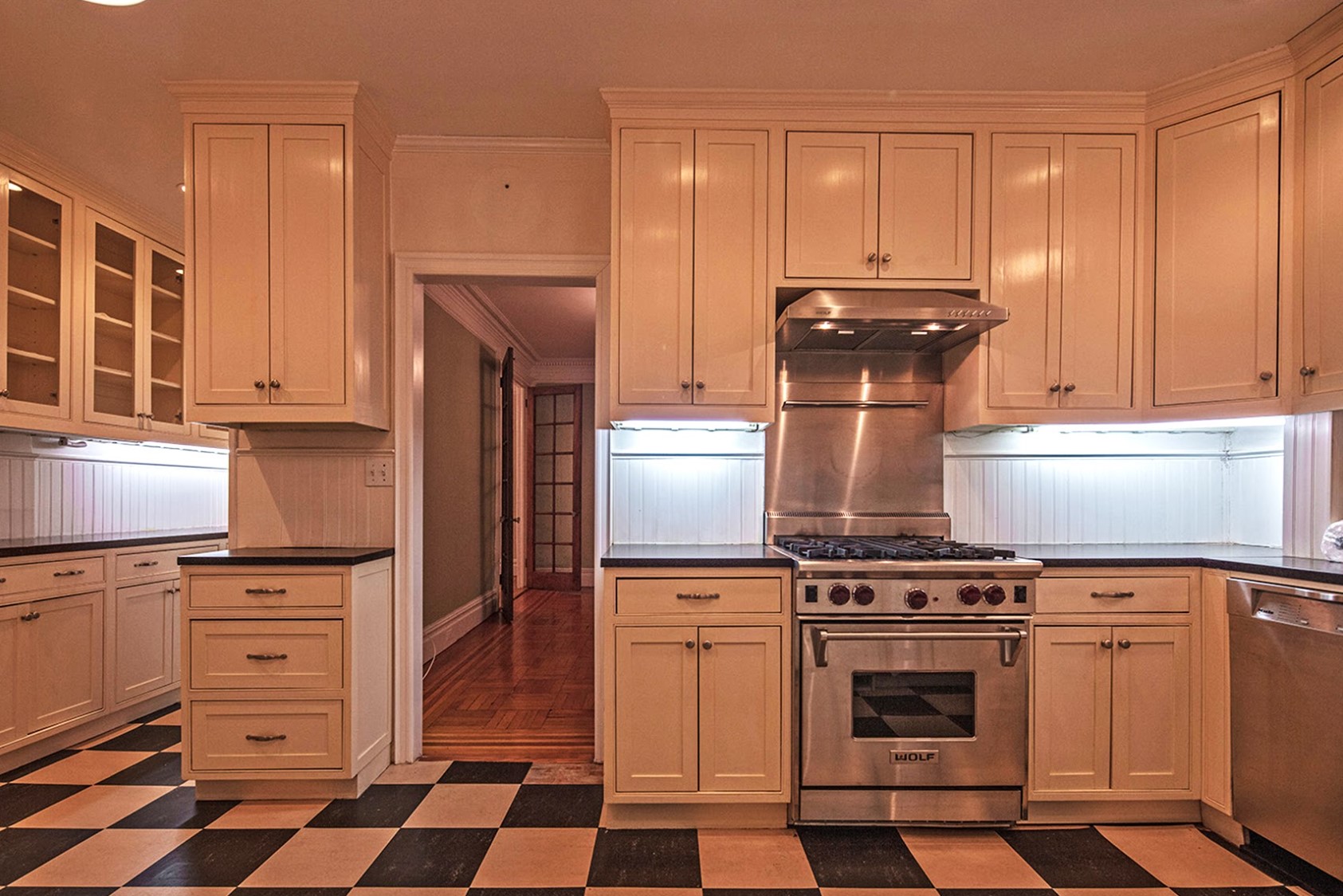 Before: A medium- size retro Kitchen with a restaurant-style range, a black and white chequered floor leads to a Butler’s Pantry on the left, and the dining room straight ahead.