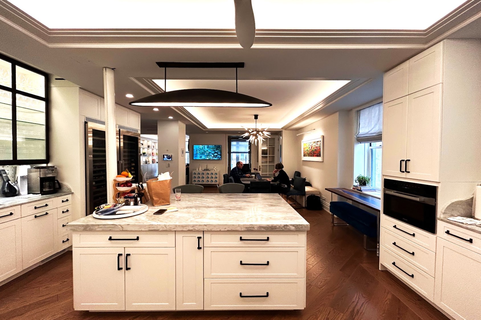 After: A large marble-topped island occupies the space where the walls between Kitchen, Dining Room, and Butler’s Pantry were. Now the floor-to-ceiling window on the other side of the apartment are visible windows.