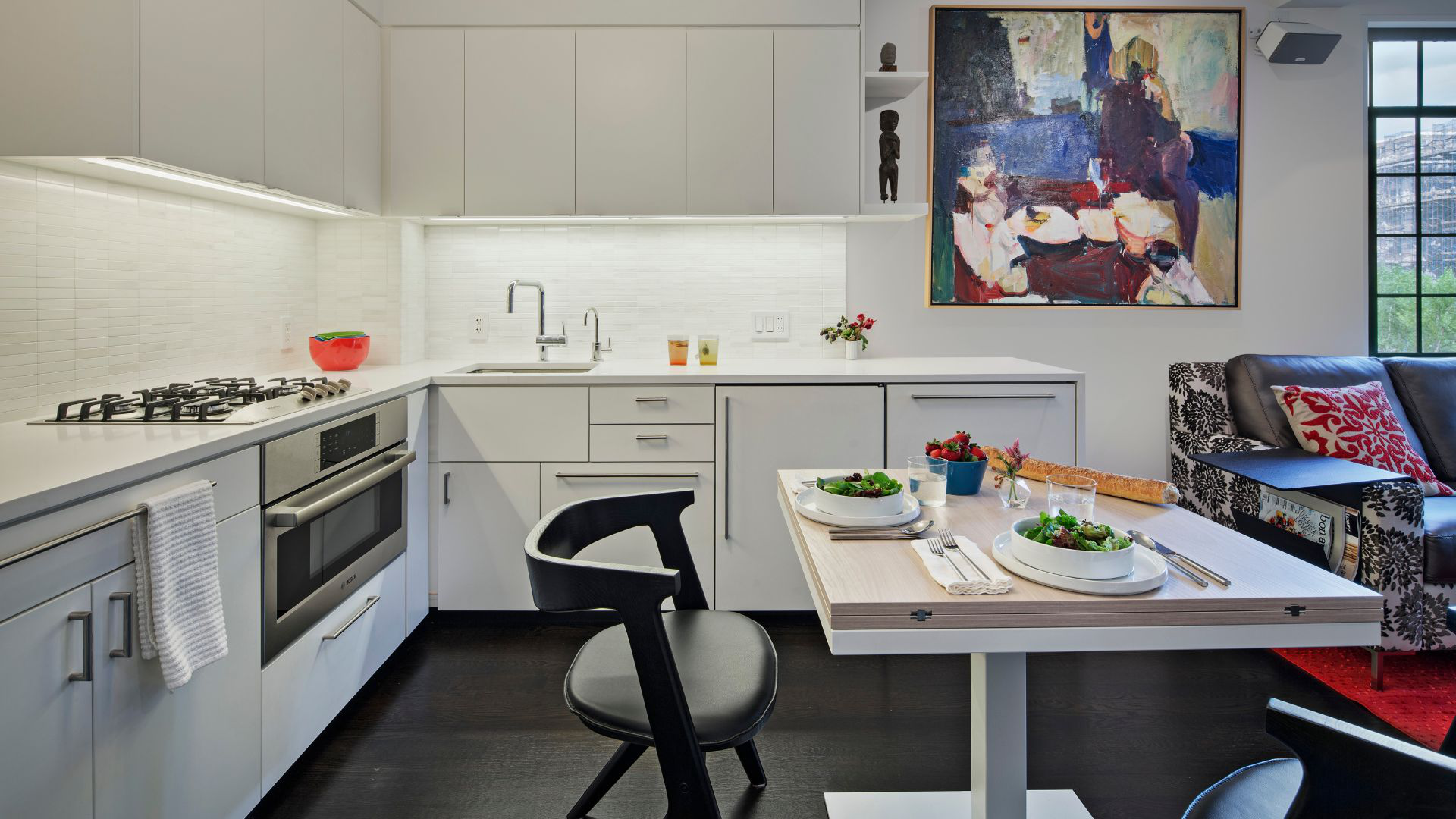 Sleek, compact white kitchen with an expandable cafe table and two chairs.